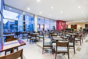基多基多智选假日酒店的餐厅设有桌椅和大窗户。