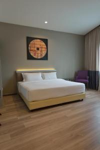 古晋阿贝尔酒店的一间卧室配有一张大床和一张紫色椅子