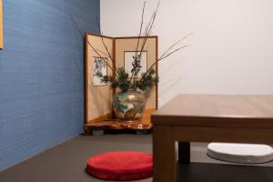 金泽Tsukuyomi Higashiyama的一间设有花瓶和一张红色凳子的桌子的房间