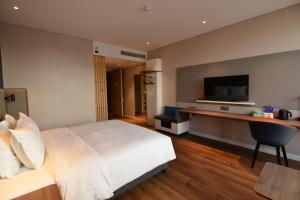 杭州杭州滨江智选假日酒店的一间卧室配有一张床和一张书桌及电视