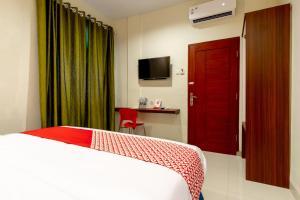 棉兰Capital O 1585 Ring Road Residence的一间酒店客房,配有一张床和一扇红色的门