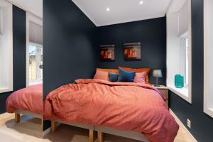 卑尔根Keyser Apartments 6的一间拥有黑色墙壁的卧室和一张带橙色床单的床