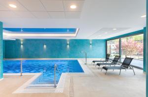 特伦钦温泉镇Wellness Hotel Panorama的一个带黑色椅子和蓝色墙壁的游泳池