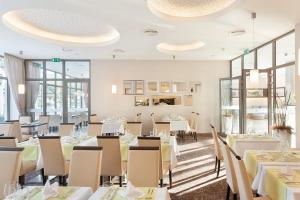 特伦钦温泉镇Hotel Panorama的餐厅设有白色的桌椅和窗户。
