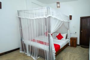 康提French Garden Kandy的卧室配有白色天蓬床和红色枕头