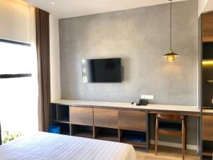 绥和市Coconut Hotel Phú Yên的卧室配有一张桌子,墙上配有电视
