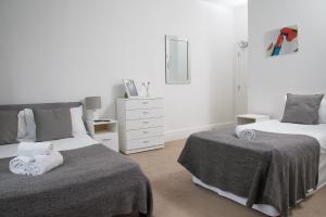 伦敦TLK Apartments & Hotel - Beckenham Junction的一间白色卧室,配有两张床和梳妆台