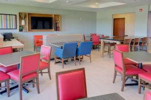 Le Mars马斯假日快捷套房酒店的用餐室配有桌子和五颜六色的椅子
