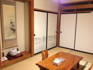 汤泽町苗场武藏宾馆的一间带桌子的用餐室和一间带推拉门的房间