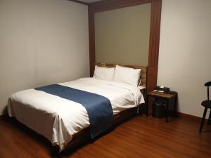 江陵市美容酒店的一间卧室配有一张带白色床单和蓝色毯子的床。