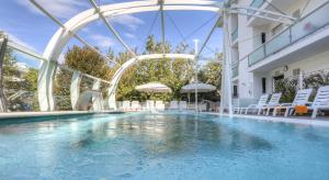 里乔内波米亚酒店 的一座带白色椅子的建筑中的游泳池和一座游泳池
