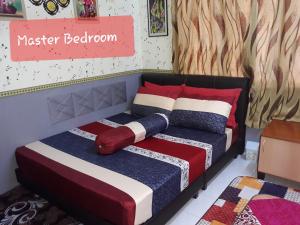 Kampong Pantai HalbanTSA Jitra Homestay的一间卧室配有一张带色彩缤纷的毯子和枕头的床。