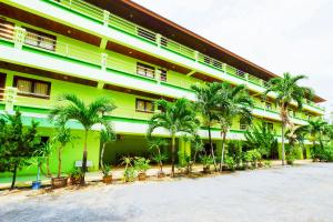 波普托Rak Samui Residence的一座绿色建筑,前面有棕榈树