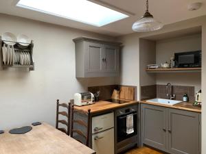 谢普顿马利特Little Doric的厨房配有灰色橱柜、水槽和桌子