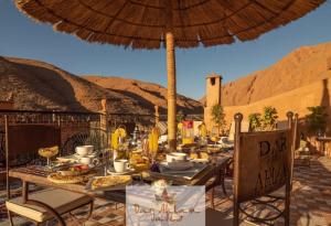 Aït OuaddarDar Ahlam Dades Hotel的露台上的桌子上摆放着食物和遮阳伞