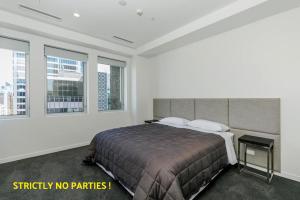 奥克兰阿克拉西亚套房公寓的一间卧室设有一张大床和两个窗户。