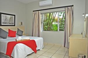 阿曼济姆托蒂Sunrise Beach Resort的一间卧室配有一张带红色毯子的床和窗户。