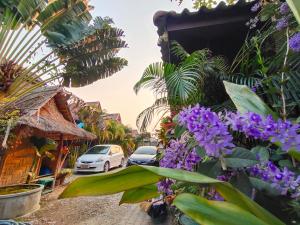美塞Bua Patumma Resort的一条有停车车和紫色花卉的街道