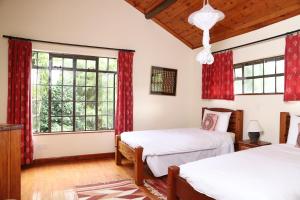 奈瓦沙Francolin Cottage at Great Rift Valley Lodge & Golf Resort Naivasha的卧室内的两张床,配有红色窗帘