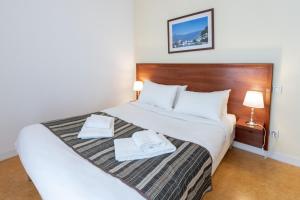 格勒诺布尔渣油格雷内特酒店的一间卧室配有一张床,上面有两条毛巾