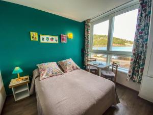 热拉梅Appart'Hôtel LIDO au bord de l'eau的一间卧室设有一张带绿色墙壁和窗户的床。
