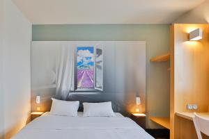 瓦朗斯B&B HOTEL Valence Sud的卧室配有白色的床和窗户。