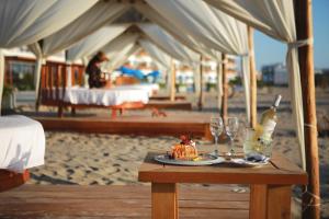 帕拉卡斯圣奥古斯丁帕拉卡斯酒店的一张桌子,上面有一块蛋糕和酒杯,放在沙滩上