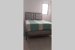 圣地亚哥洛斯卡巴Amplio y acogedor apartamento的一间卧室配有一张带绿色和白色毯子的床