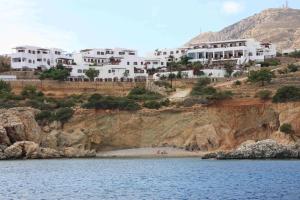 阿莫皮Aegean Village Beachfront Resort的水边悬崖上的一群白色房屋