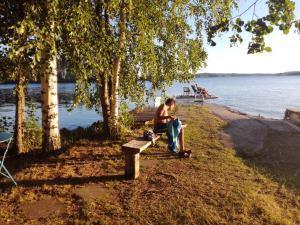 LintusaloNestorinranta Resort的坐在水边长凳上的男人
