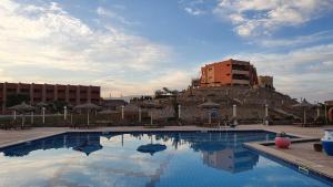 艾因苏赫纳Fanar Hotel的一座大型游泳池,其建筑背景为: