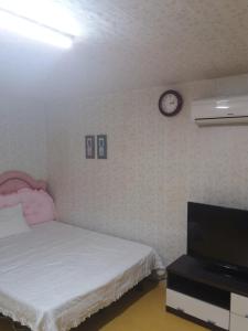 襄阳郡Dasanbang Pension的卧室配有一张床,墙上挂着一个钟