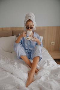 梅斯蒂亚Hotel panorama svaneti的坐在床上喝一杯咖啡的女人