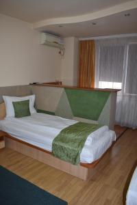 克卢日-纳波卡珍布鲁酒店的一间卧室配有一张带绿毯的大床