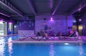 贝辛斯托克Village Hotel Basingstoke的砖墙旁带椅子的游泳池