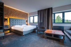 吕贝克吕贝克丽笙公园酒店的一间卧室配有一张床、一把椅子和一张沙发