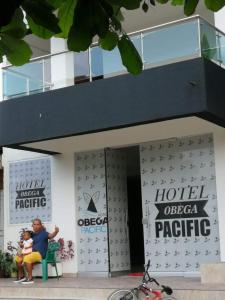努基Hotel OBEGA PACIFIC的坐在酒店前方长凳上的女人