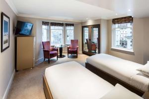 伦敦Radisson Blu Edwardian Bloomsbury Street Hotel, London的酒店客房带两张床和一张桌子以及椅子。