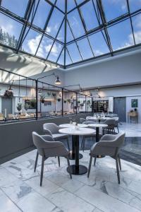 奥胡斯奥尔胡斯蓝色雷迪森北欧酒店的餐厅设有桌椅和玻璃天花板