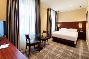 伦敦Radisson Blu Vanderbilt Hotel, London的酒店客房配有一张床、一张书桌和一台电视。