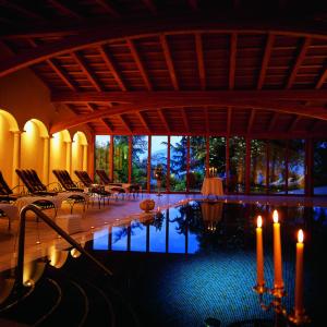 阿皮亚诺苏拉斯特拉达Schloss Hotel Korb的一间带椅子和蜡烛的游泳池的客房