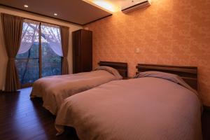 阿苏市千之森旅馆的配有窗户的酒店客房内的两张床