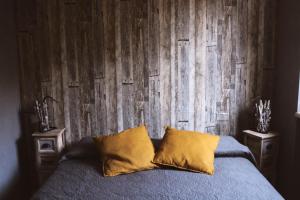 蒂沃利ApartHotel Le Sirene - CHALET的木墙前的一张带两个枕头的床