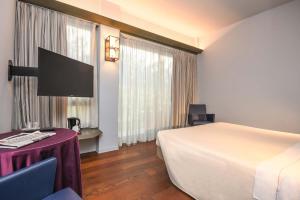 代森扎诺-德尔加达城市酒店的一间酒店客房,配有一张床铺、一张桌子和一台电视