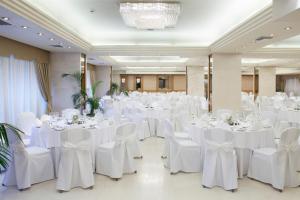 塞萨洛尼基塞萨洛尼基假日酒店 的宴会厅配有白色的桌椅