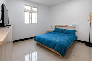 北竿一九六民宿的一间卧室配有一张带蓝色床单的床和电视。