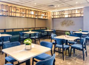 广州锦江都城酒店(广州白云站江南市场店)的一间配备有桌子和蓝色椅子的用餐室