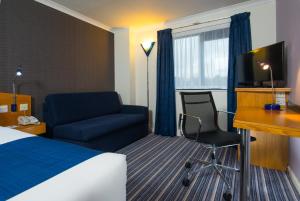 曼彻斯特快捷假日曼切斯特东区酒店的酒店客房配有一张床、一张桌子和一把椅子。