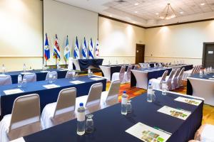 圣萨尔瓦多圣萨尔瓦多假日酒店的一间设有蓝色桌子、白色椅子和旗帜的房间