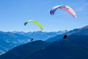 齐勒河谷采尔加尼马克西米利安酒店的两个人在空中骑着风筝,越过山